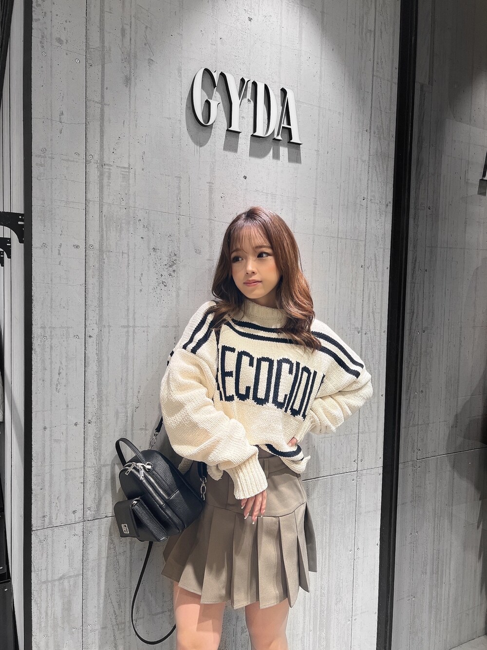 ベージュ系のスカート、ホワイト系のニット/セーター、ブラック系のブーツを着用したレディースの冬コーディネートの2枚目の写真