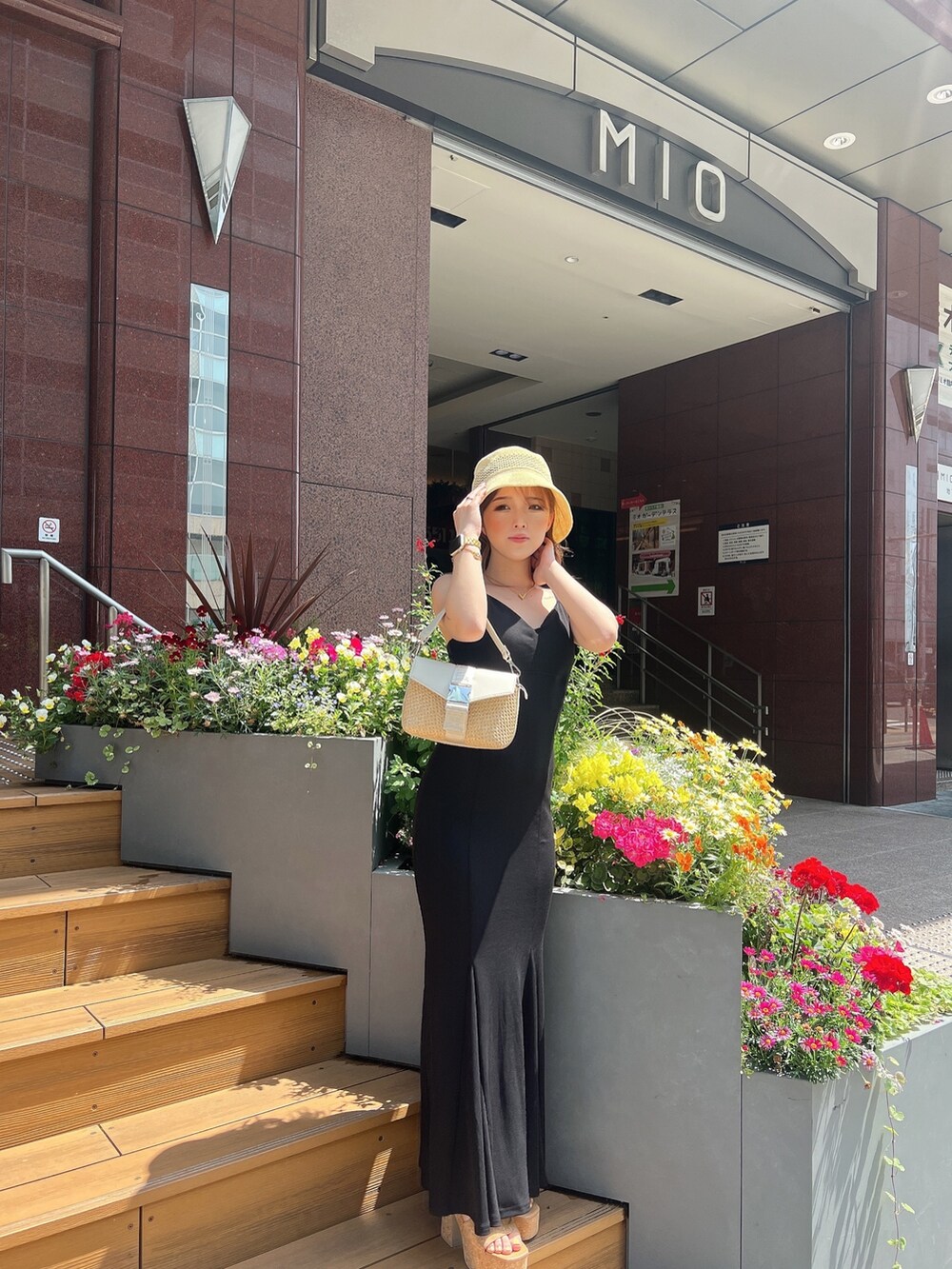 ブラック系のワンピース、ホワイト系のサンダル、ホワイト系のハンドバッグを着用したレディースの春コーディネートの2枚目の写真