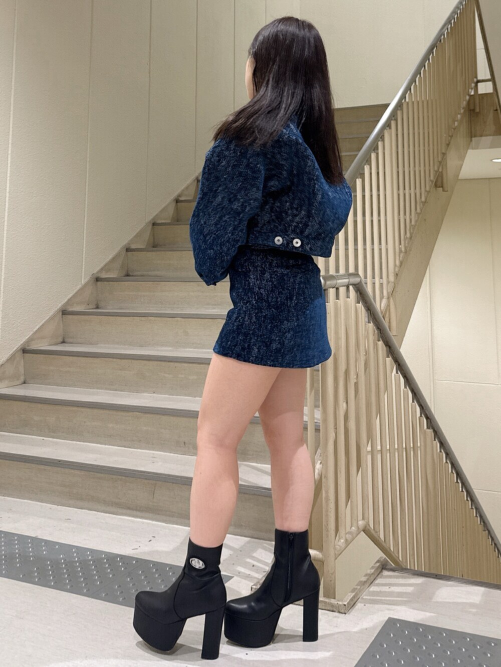 ブルー系のデニムジャケット、ブルー系のスカート、ホワイト系のキャミソールを着用したレディースの冬コーディネートの2枚目の写真