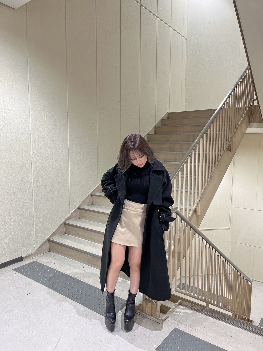 ブラック系のニット/セーター、ブラック系のトレンチコート、ブラック系のブーツを着用したレディースの冬コーディネートの2枚目の写真