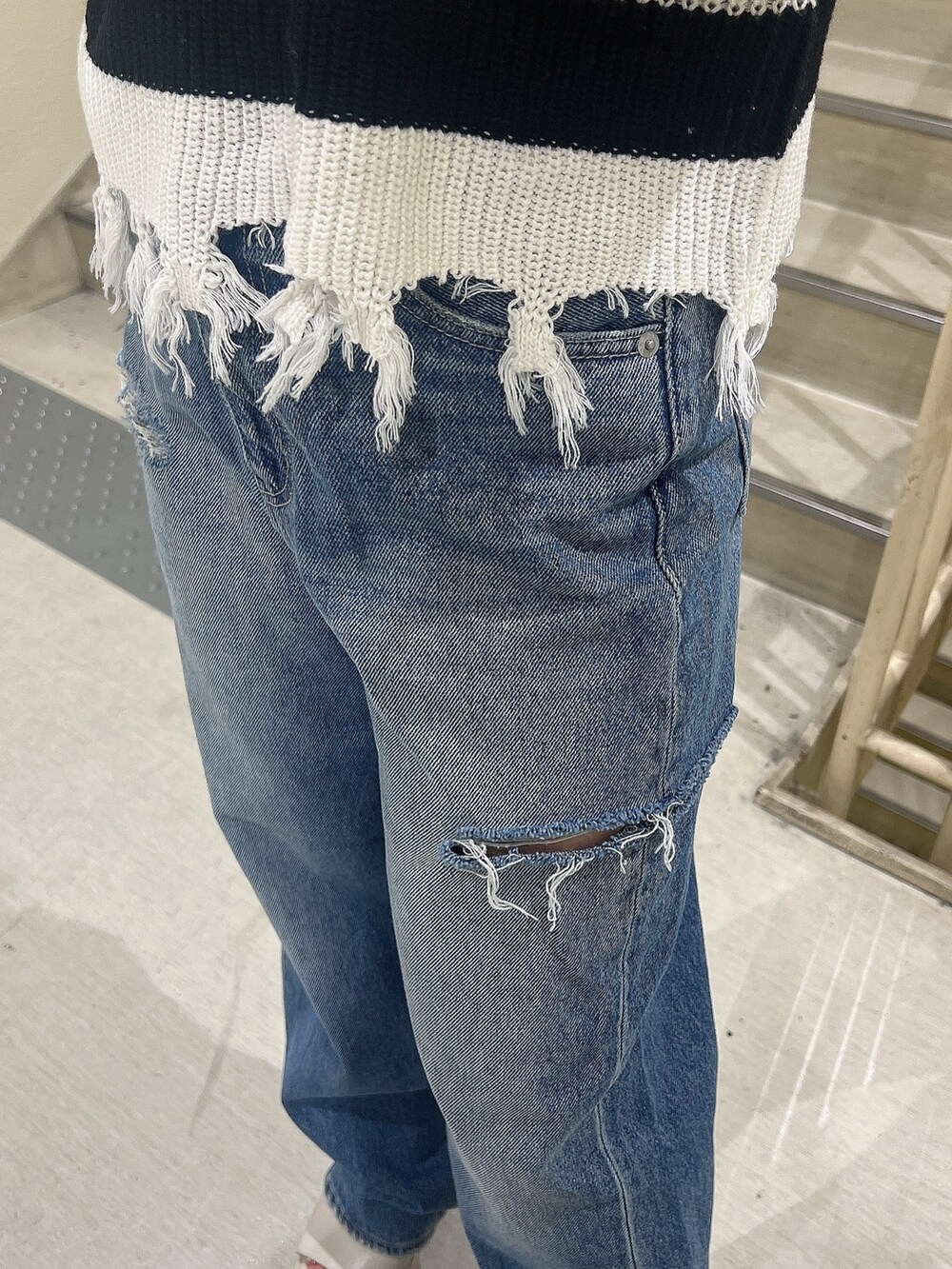 ブルー系のデニムパンツ、ブラック系のニット/セーター、ホワイト系のサンダルを着用したレディースの夏コーディネートの7枚目の写真