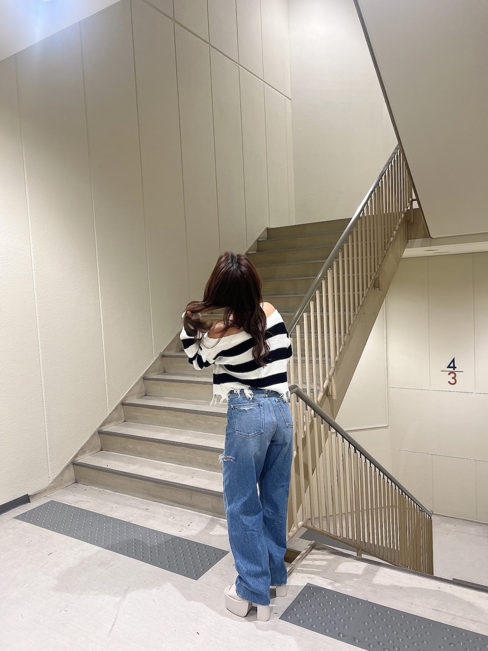 ブルー系のデニムパンツ、ブラック系のニット/セーター、ホワイト系のサンダルを着用したレディースの夏コーディネートの3枚目の写真