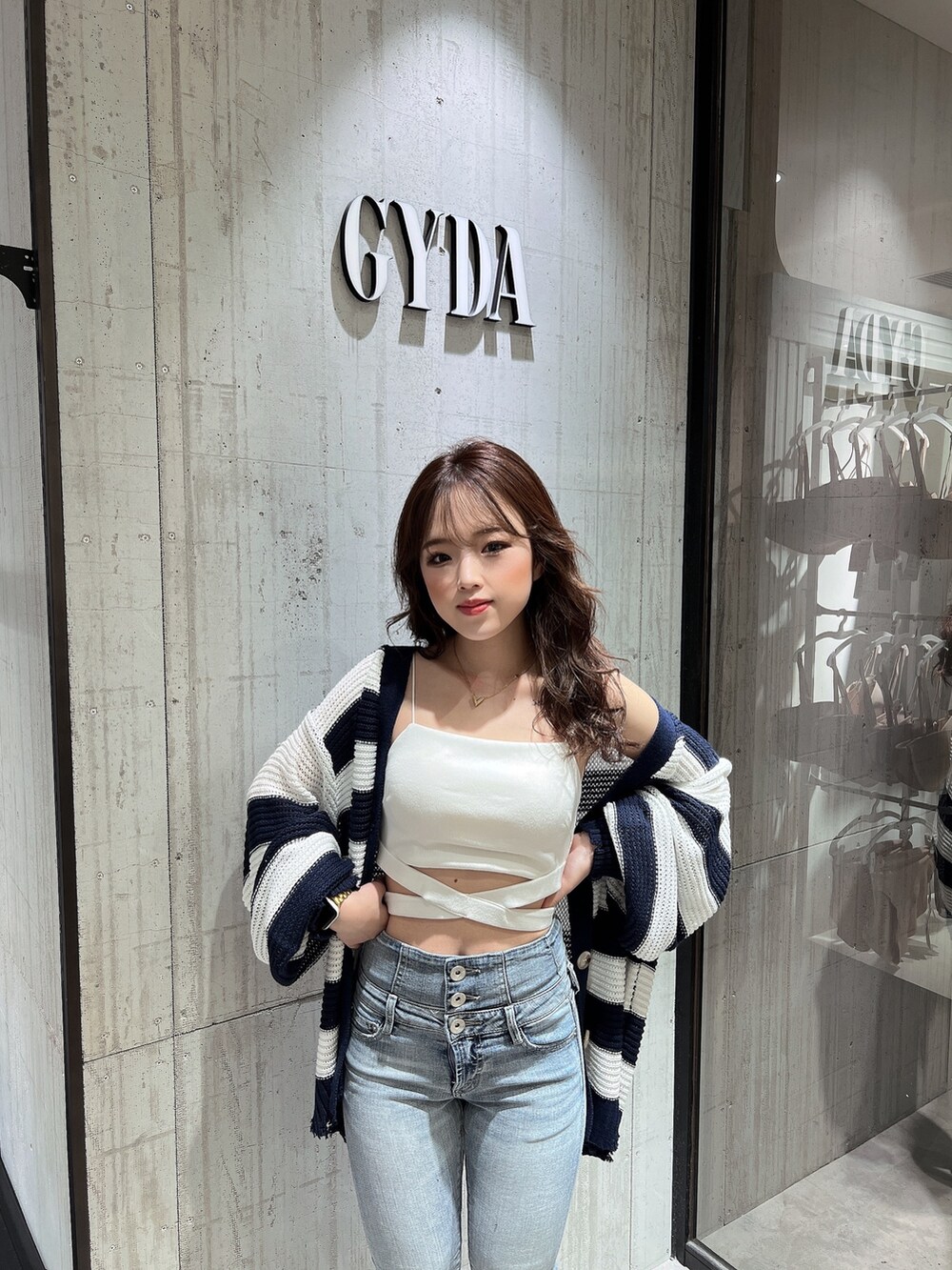 ブルー系のデニムパンツ、ブルー系のカーディガン/ボレロ、ホワイト系のキャミソールを着用したレディースの夏コーディネートの6枚目の写真