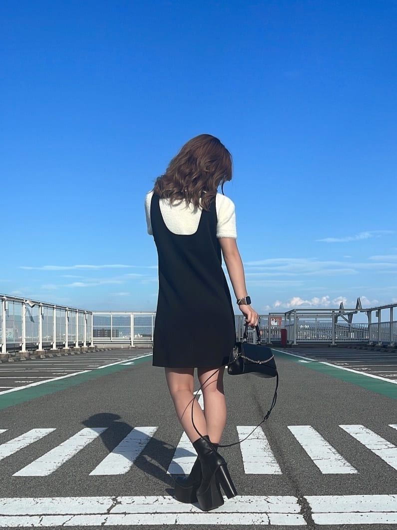 ホワイト系のニット/セーター、ブラック系のハンドバッグ、ブラック系のブーツを着用したレディースの夏コーディネートの2枚目の写真