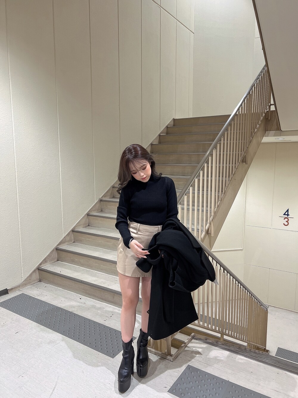 ブラック系のニット/セーター、ブラック系のトレンチコート、ブラック系のブーツを着用したレディースの冬コーディネートの6枚目の写真