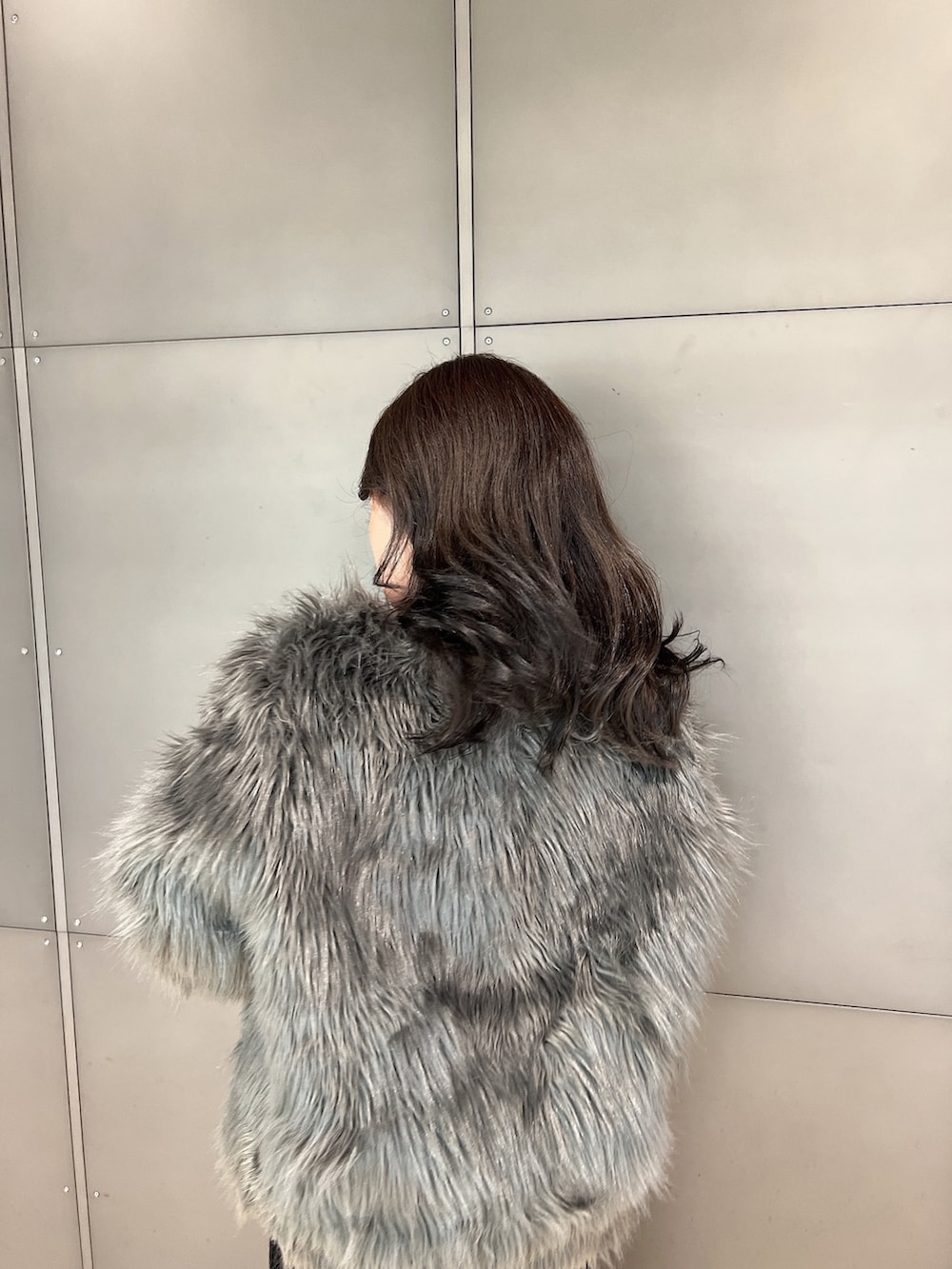 グレー系のライダースジャケット、ブラック系のワンピース、ブラック系のブーツを着用したレディースの冬コーディネートの4枚目の写真