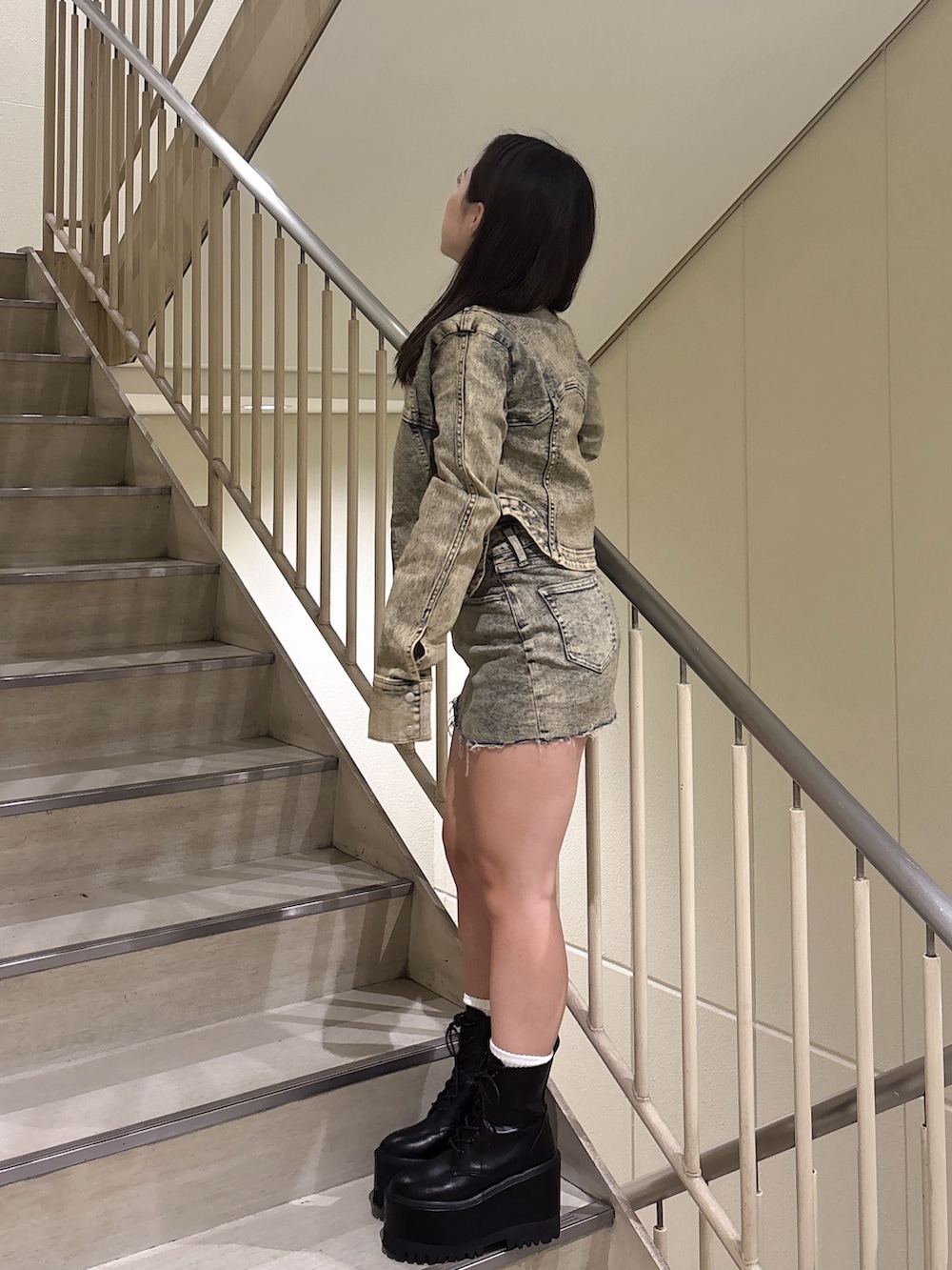 ブルー系のデニムジャケット、ブルー系のデニムスカート、ブラック系のブーツを着用したレディースの秋コーディネートの2枚目の写真