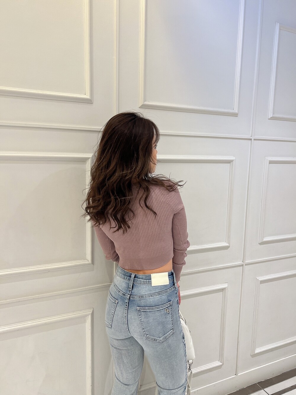 ピンク系のニット/セーター、ブルー系のデニムパンツ、ホワイト系のバックパック/リュックを着用したレディースの冬コーディネートの6枚目の写真