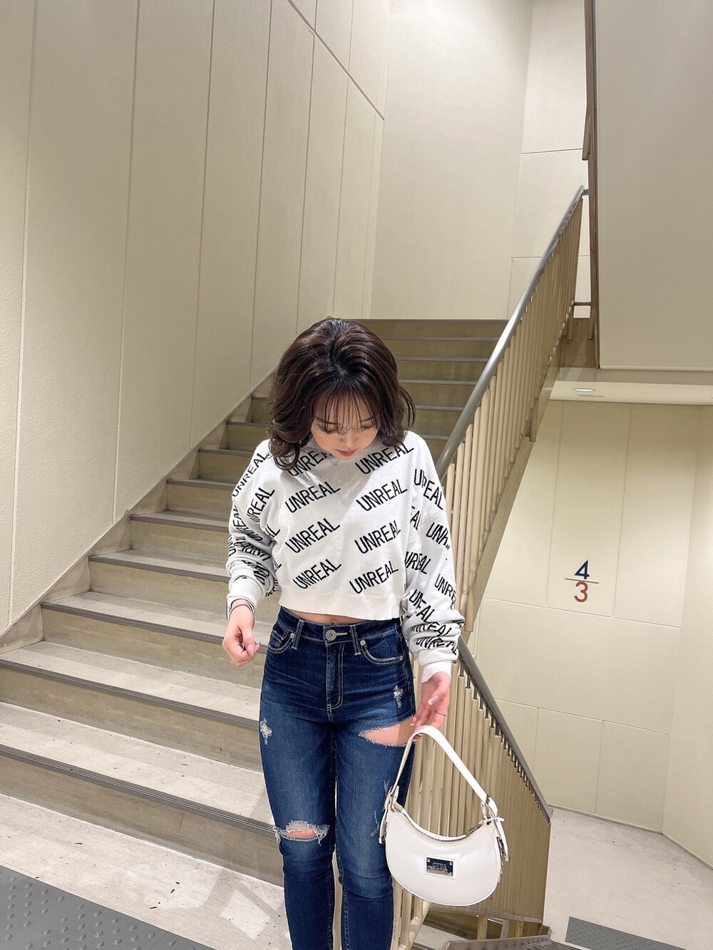 ホワイト系のニット/セーター、ブルー系のデニムパンツ、ホワイト系のハンドバッグを着用したレディースの冬コーディネートの3枚目の写真