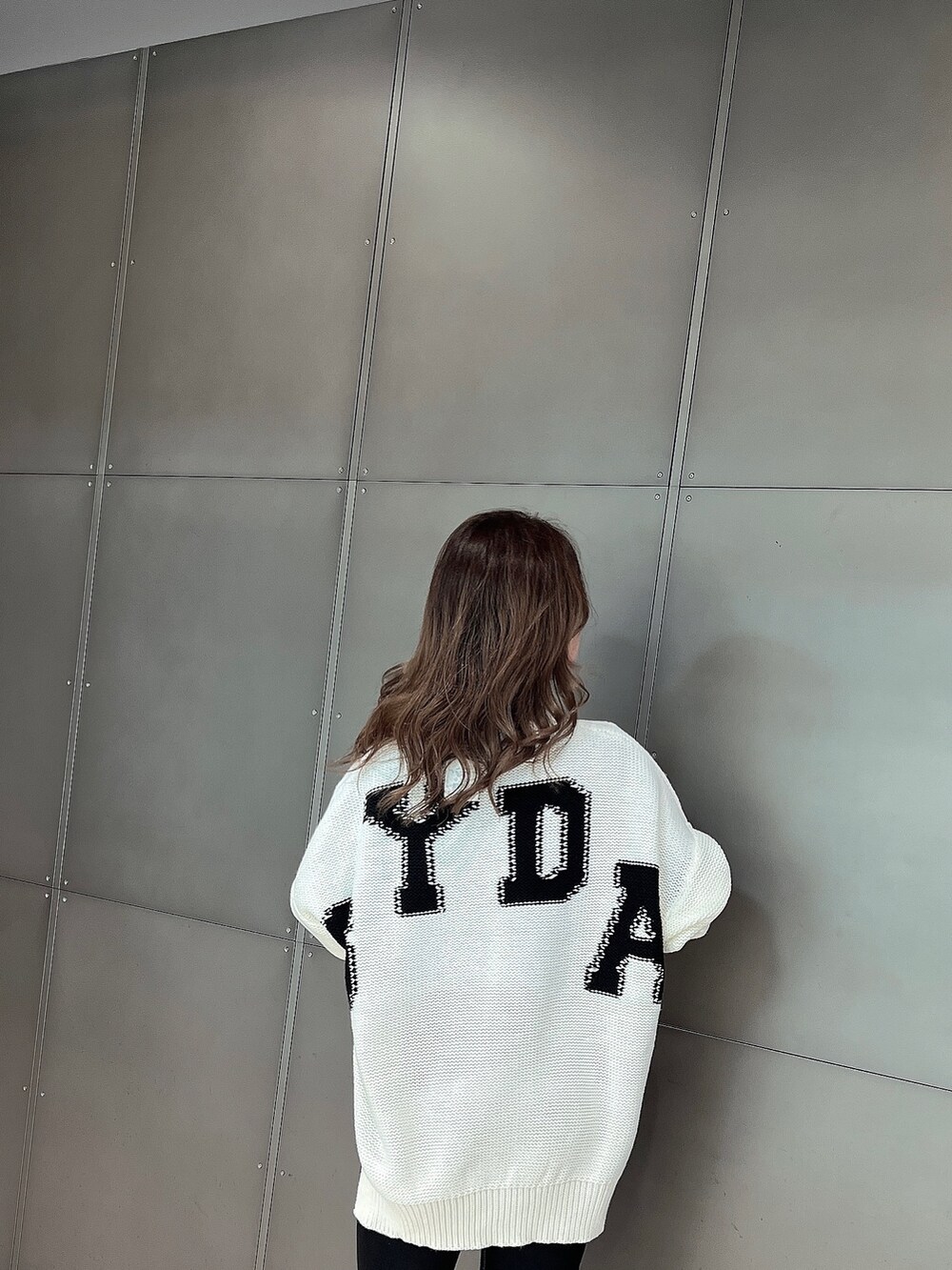 ホワイト系のニット/セーター、ブラック系のデニムパンツ、ホワイト系のパンプスを着用したレディースの冬コーディネートの4枚目の写真