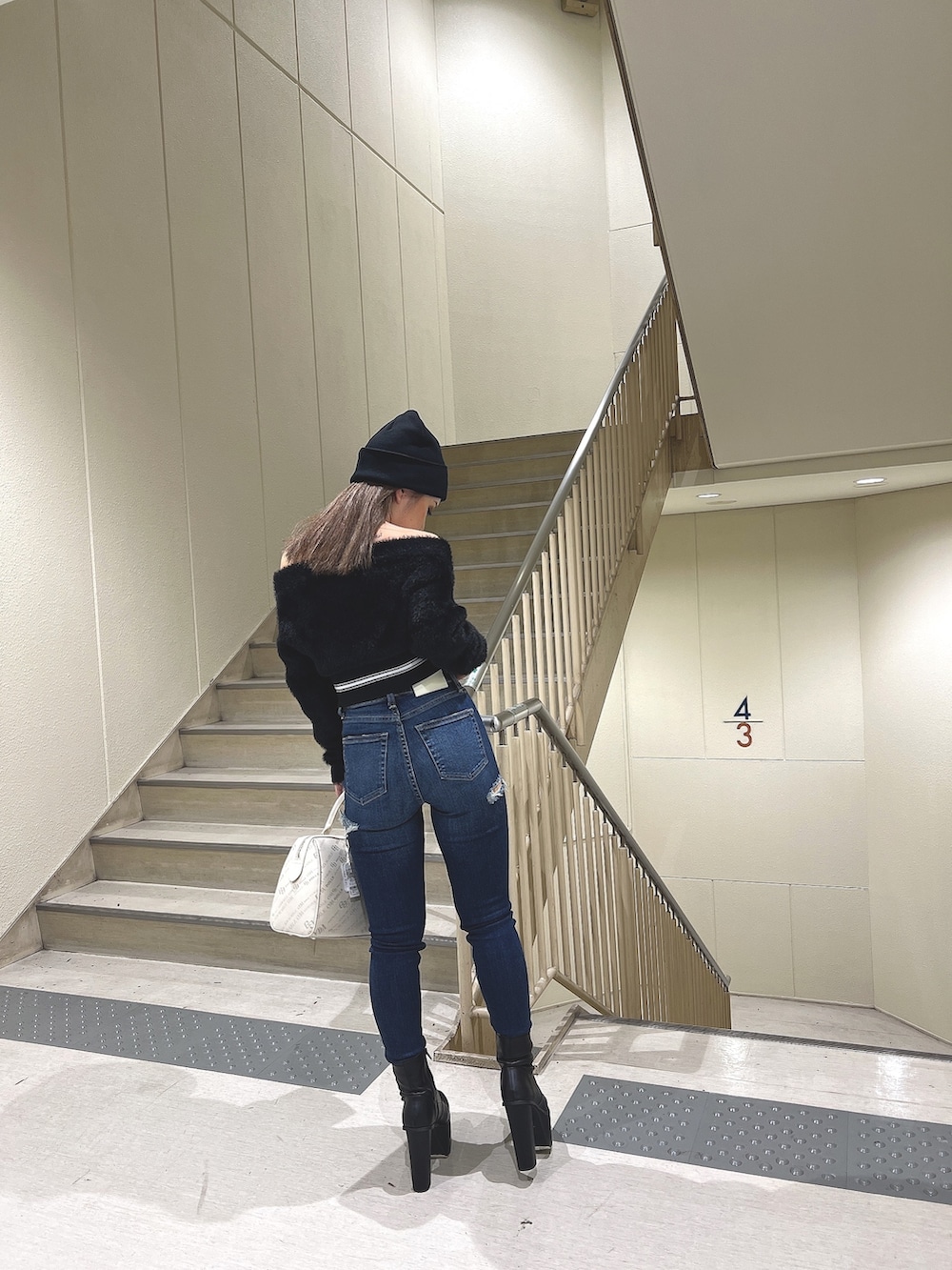 ブラック系のニット/セーター、ブルー系のデニムパンツ、ブラック系のブーツを着用したレディースの秋コーディネートの6枚目の写真