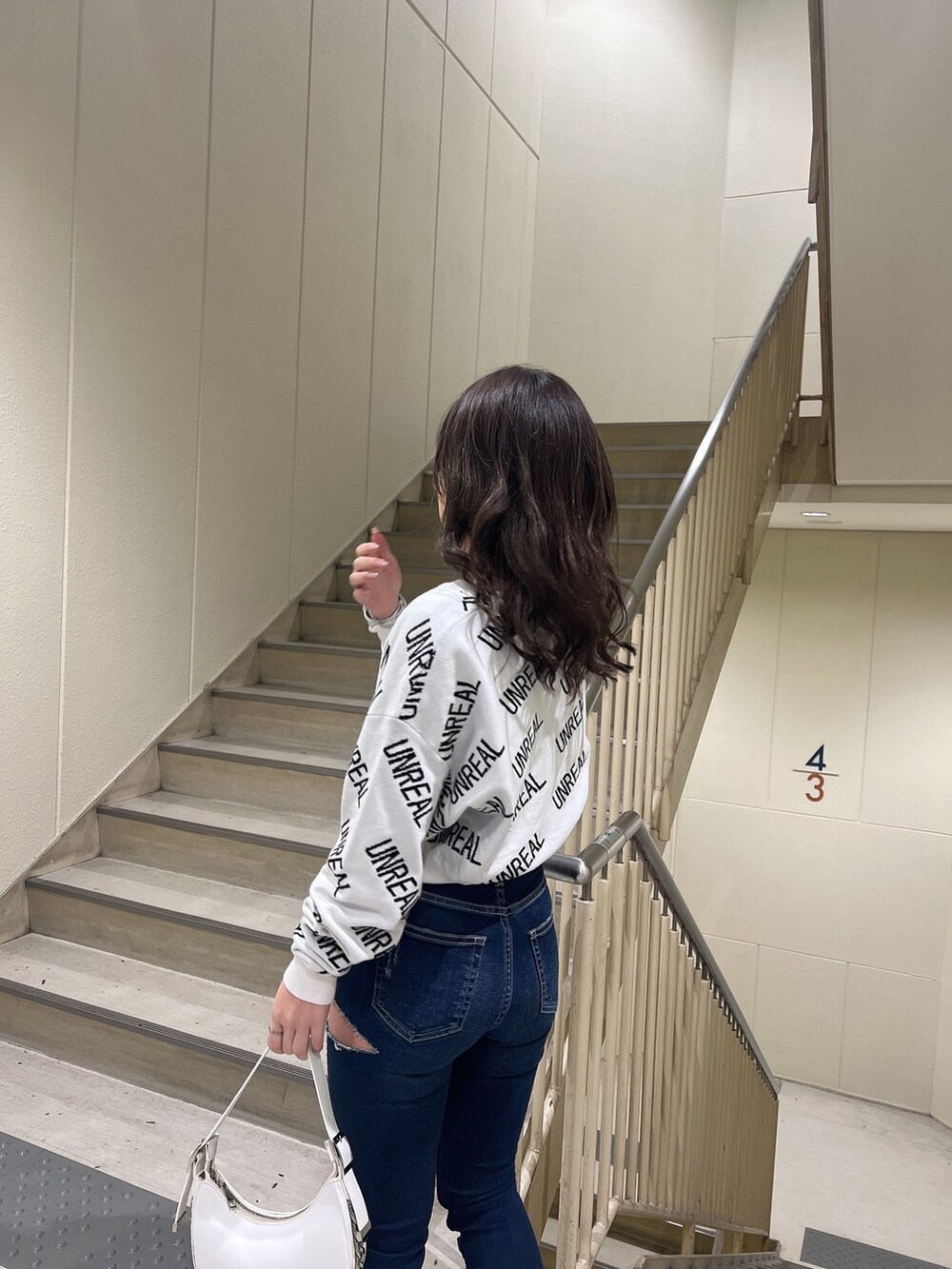 ホワイト系のニット/セーター、ブルー系のデニムパンツ、ホワイト系のハンドバッグを着用したレディースの冬コーディネートの5枚目の写真