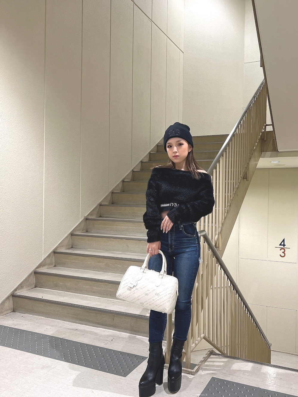 ブラック系のニット/セーター、ブルー系のデニムパンツ、ブラック系のブーツを着用したレディースの秋コーディネートの2枚目の写真