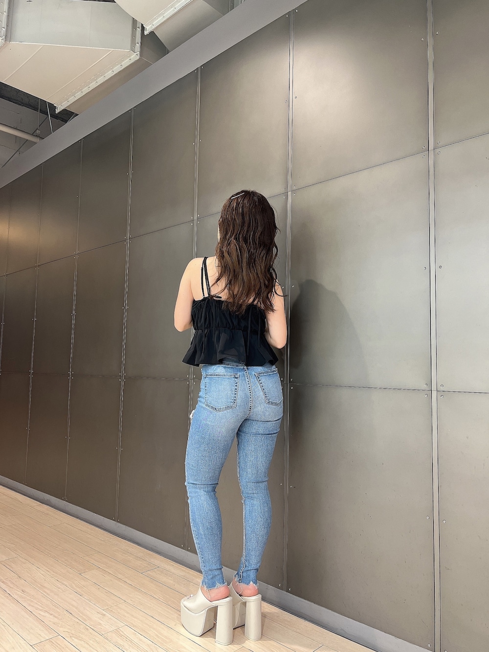 ブラック系のキャミソール、ブルー系のデニムパンツ、ホワイト系のサンダルを着用したレディースの夏コーディネートの2枚目の写真