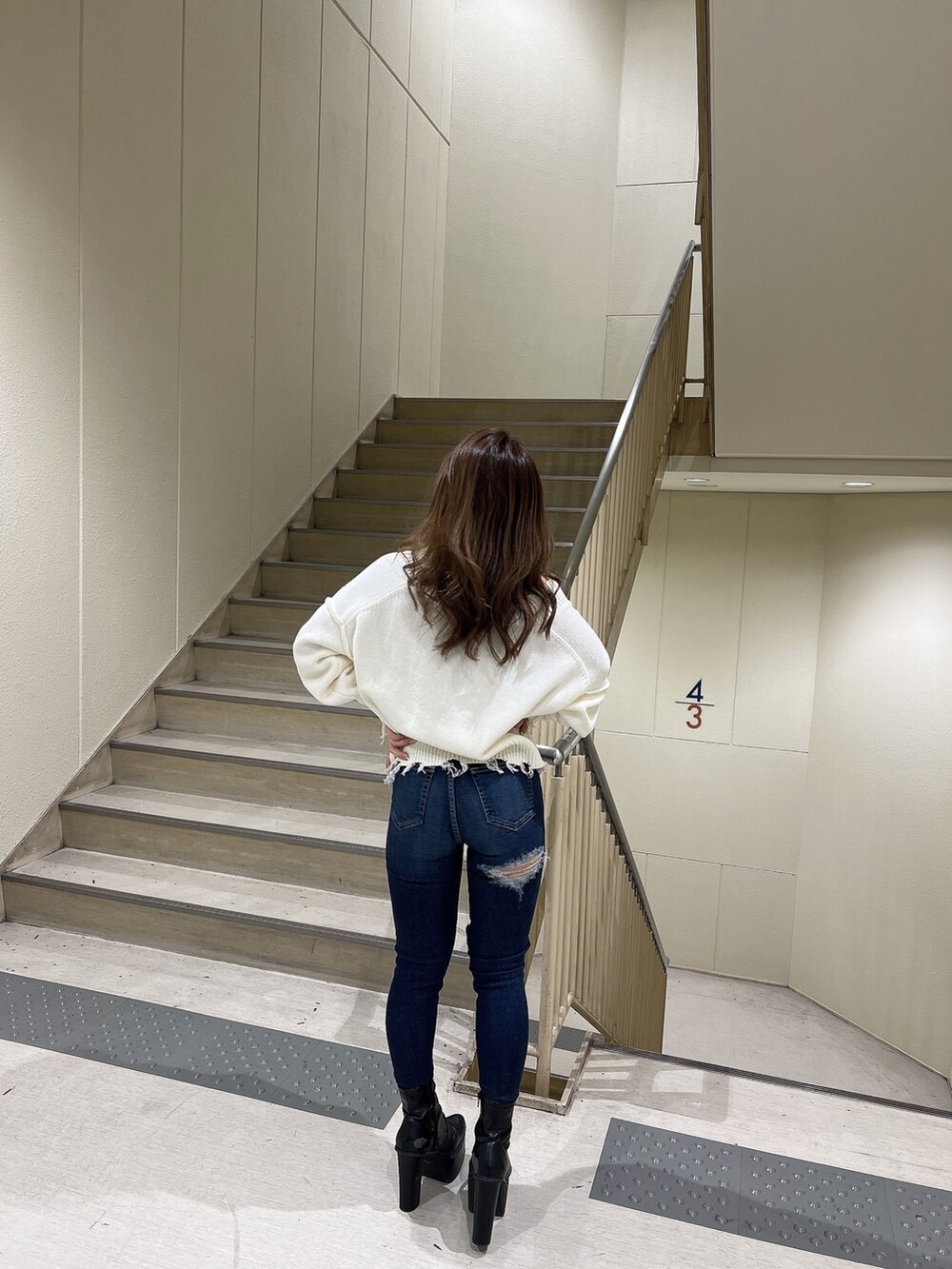 ブルー系のデニムパンツ、ホワイト系のニット/セーター、ブラック系のブーツを着用したレディースの冬コーディネートの5枚目の写真