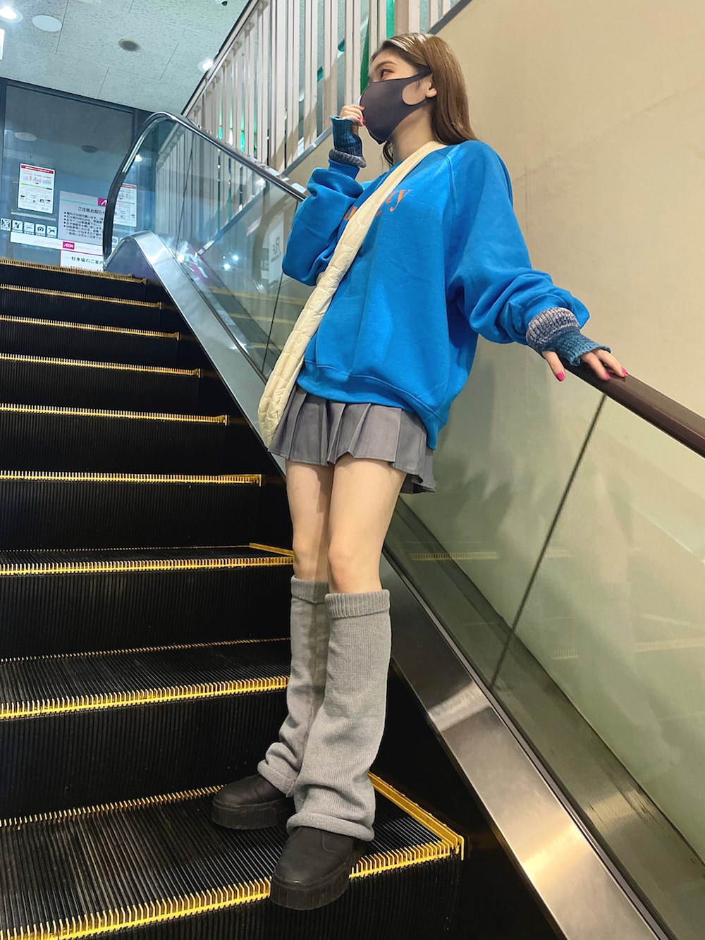 ホワイト系のショルダーバッグ、グレー系のスカート、ブラック系のスニーカーを着用したレディースの秋コーディネートの2枚目の写真