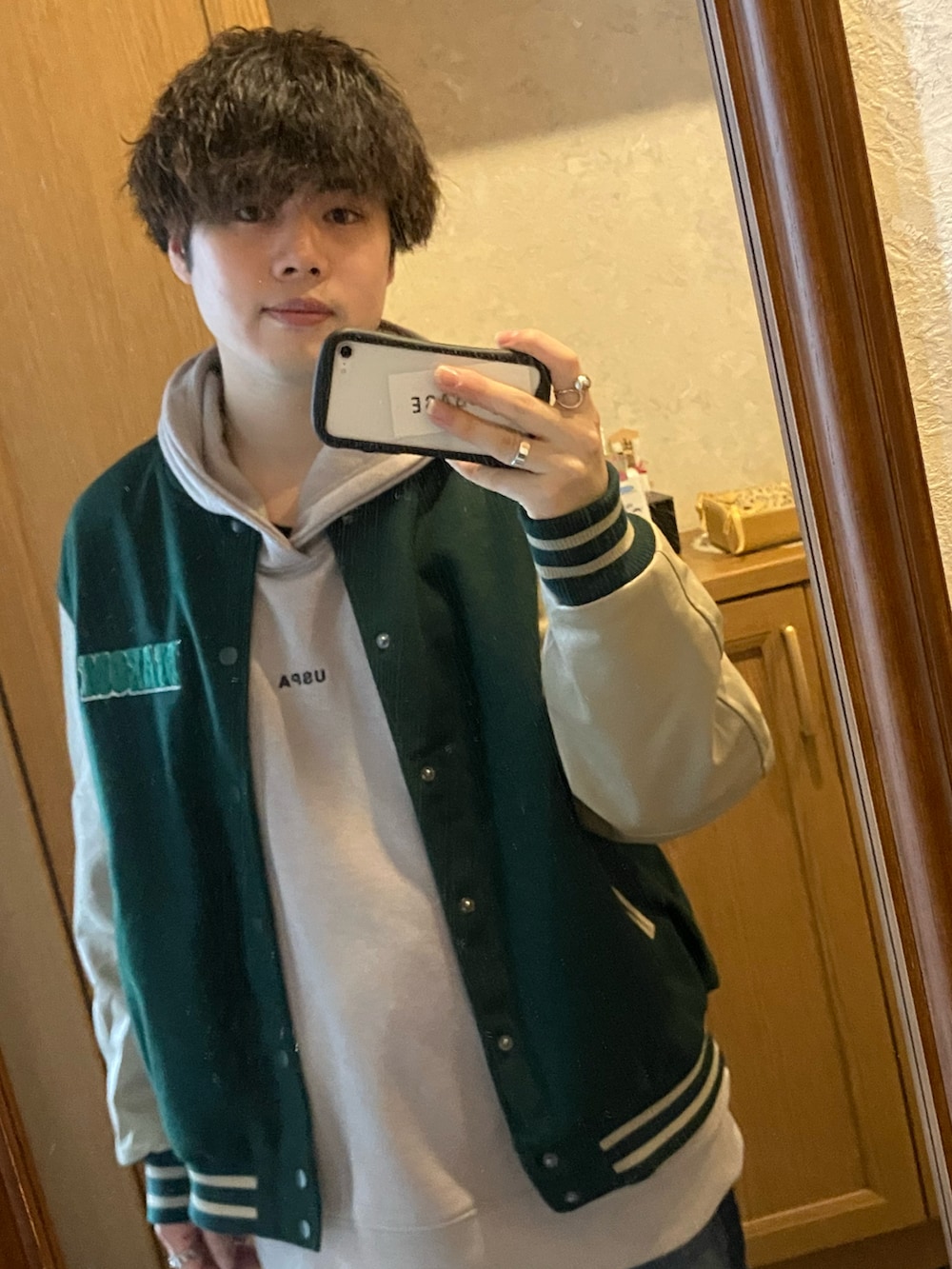 ブルー系のデニムパンツ、ブルー系のスタジャン、ベージュ系のパーカーを着用したメンズの春コーディネートの2枚目の写真