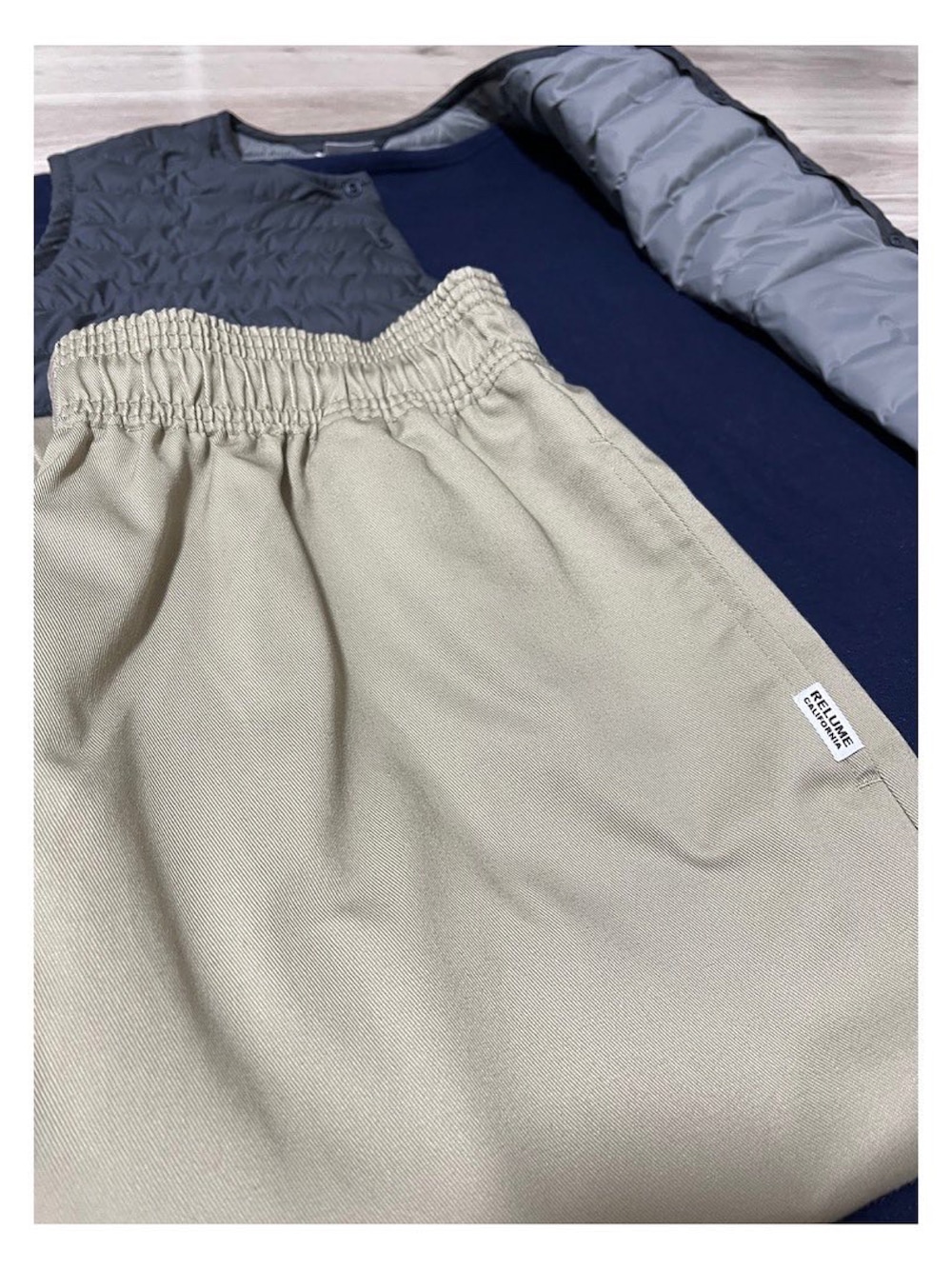 ベージュ系のチノパンツ、グレー系のダウンベスト、ブルー系のTシャツ/カットソーを着用したメンズの秋コーディネートの2枚目の写真