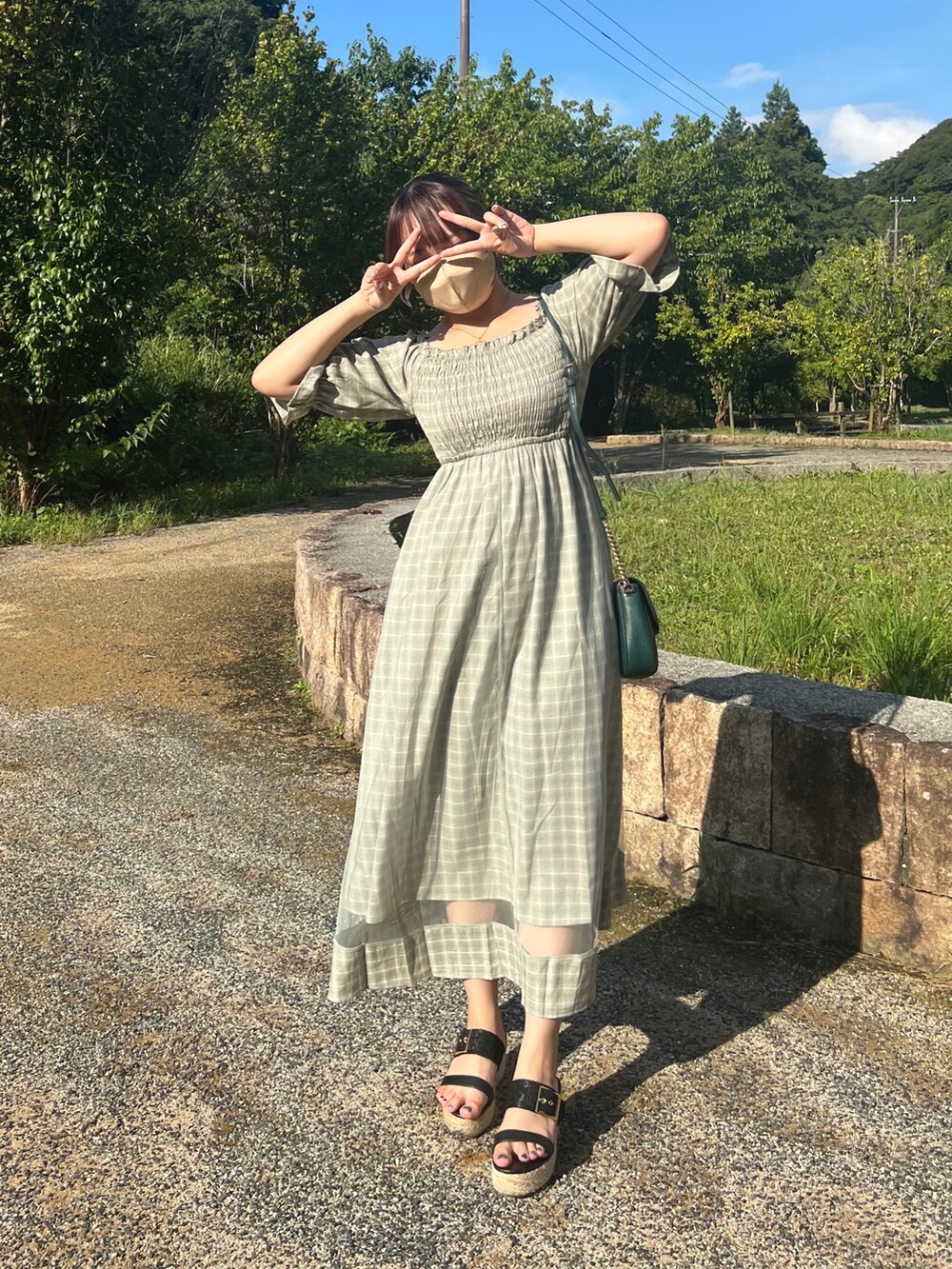 グリーン系のワンピース、グリーン系のショルダーバッグを着用したレディースの夏コーディネートの2枚目の写真