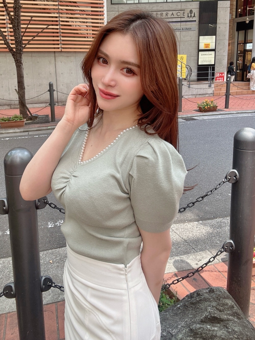 グリーン系のニット/セーター、ホワイト系のスカートを着用したレディースの春コーディネートの2枚目の写真