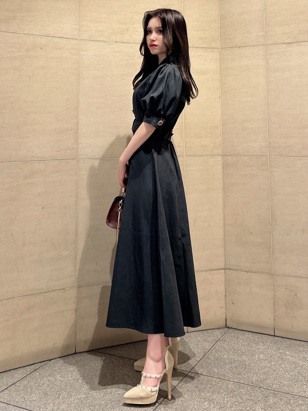 ブラック系のワンピース、ブラウン系のハンドバッグ、ベージュ系のパンプスを着用したレディースの春コーディネートの2枚目の写真