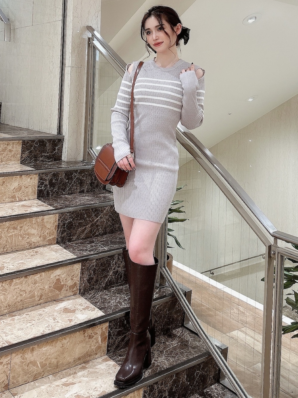 グレー系のワンピース、ブラウン系のブーツ、イエロー系のショルダーバッグを着用したレディースの秋コーディネートの2枚目の写真