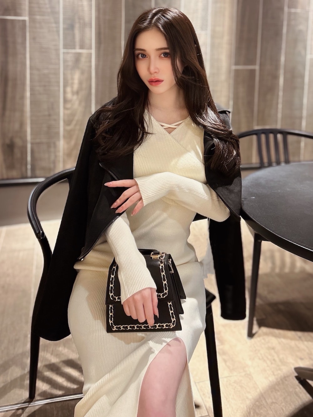 ブラック系のハンドバッグ、ホワイト系のワンピース、ブラック系のライダースジャケットを着用したレディースの冬コーディネートの2枚目の写真