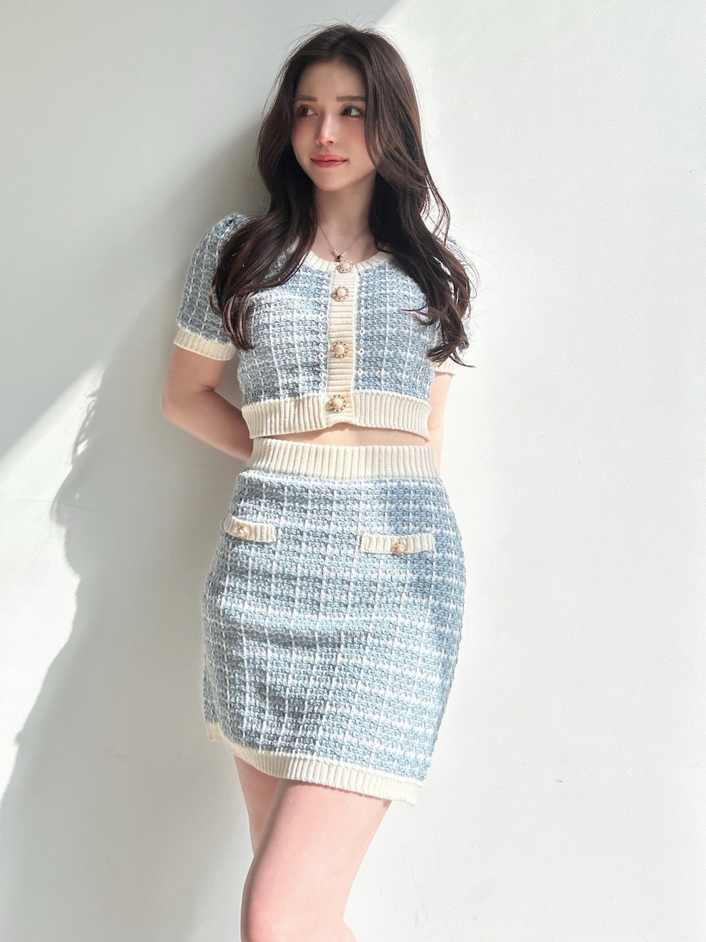 ブルー系のニット/セーター、ブルー系のスカート、ホワイト系のショルダーバッグを着用したレディースの春コーディネートの3枚目の写真