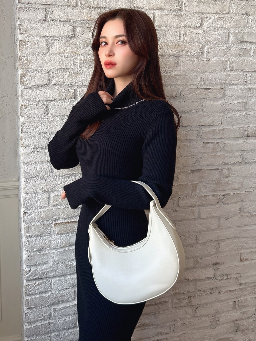 ブラック系のワンピース、ブラック系のブーツ、ブラック系のハンドバッグを着用したレディースの冬コーディネートの2枚目の写真