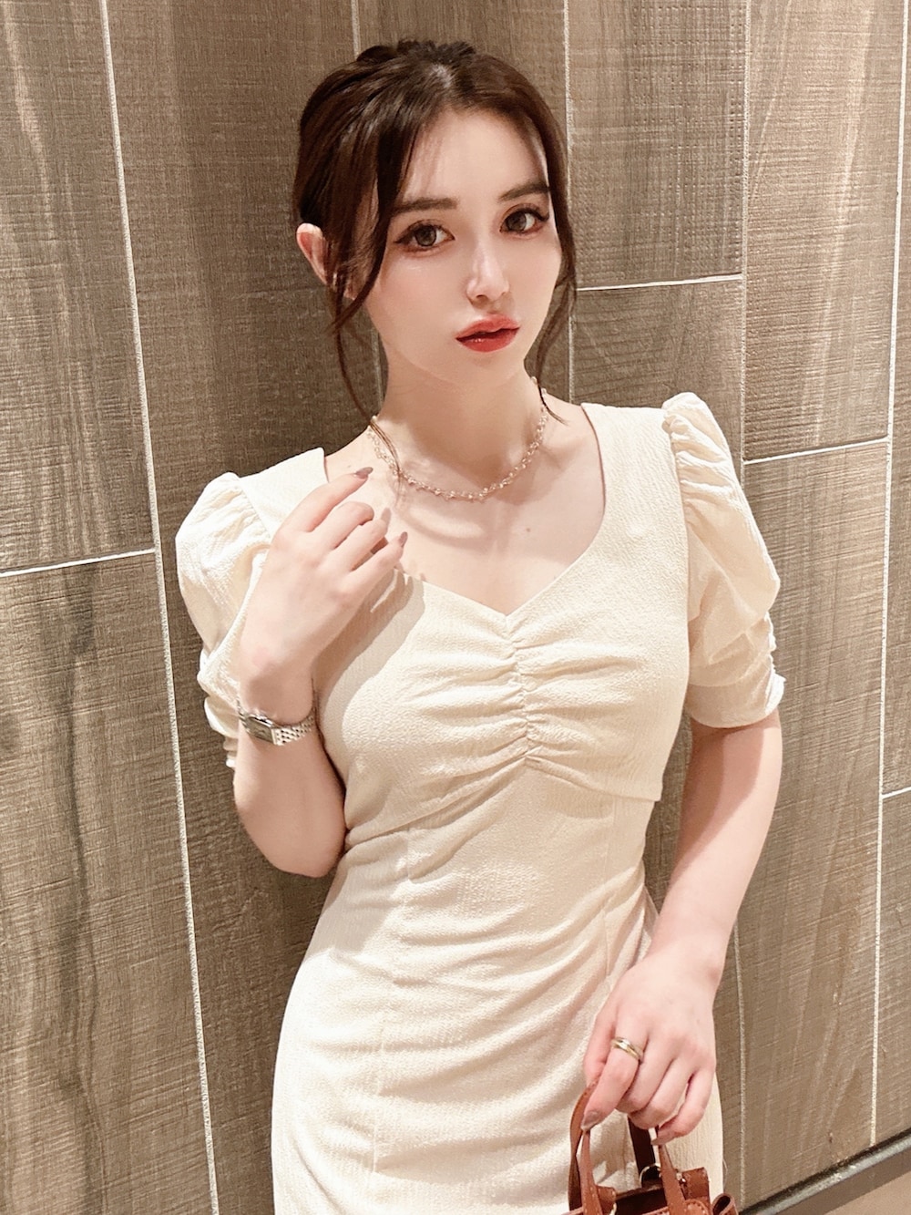 ホワイト系のワンピース、ブラウン系のハンドバッグ、ゴールド系のネックレスを着用したレディースの秋コーディネートの2枚目の写真