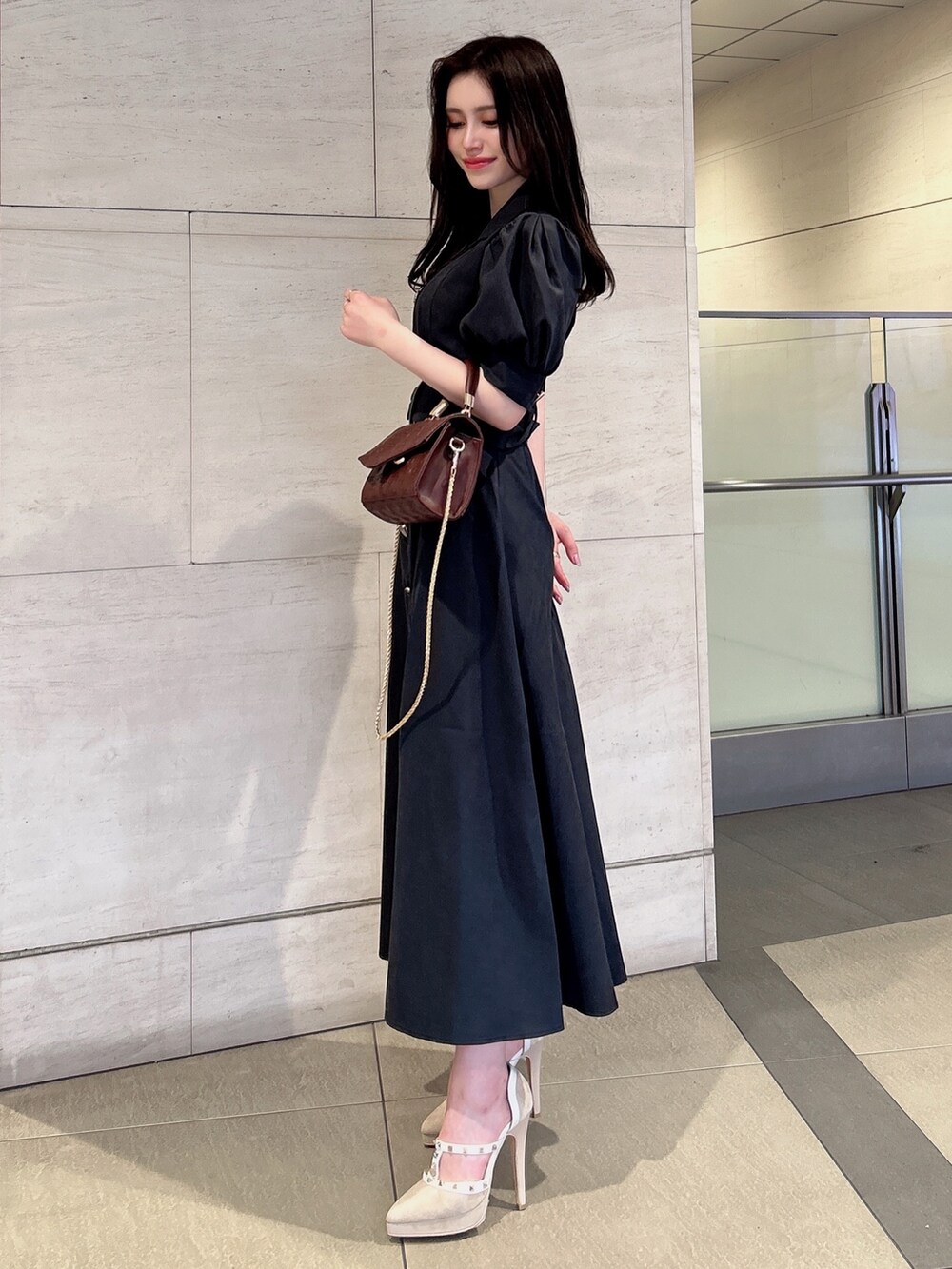 ブラック系のワンピース、ブラウン系のハンドバッグ、ベージュ系のパンプスを着用したレディースの春コーディネートの3枚目の写真