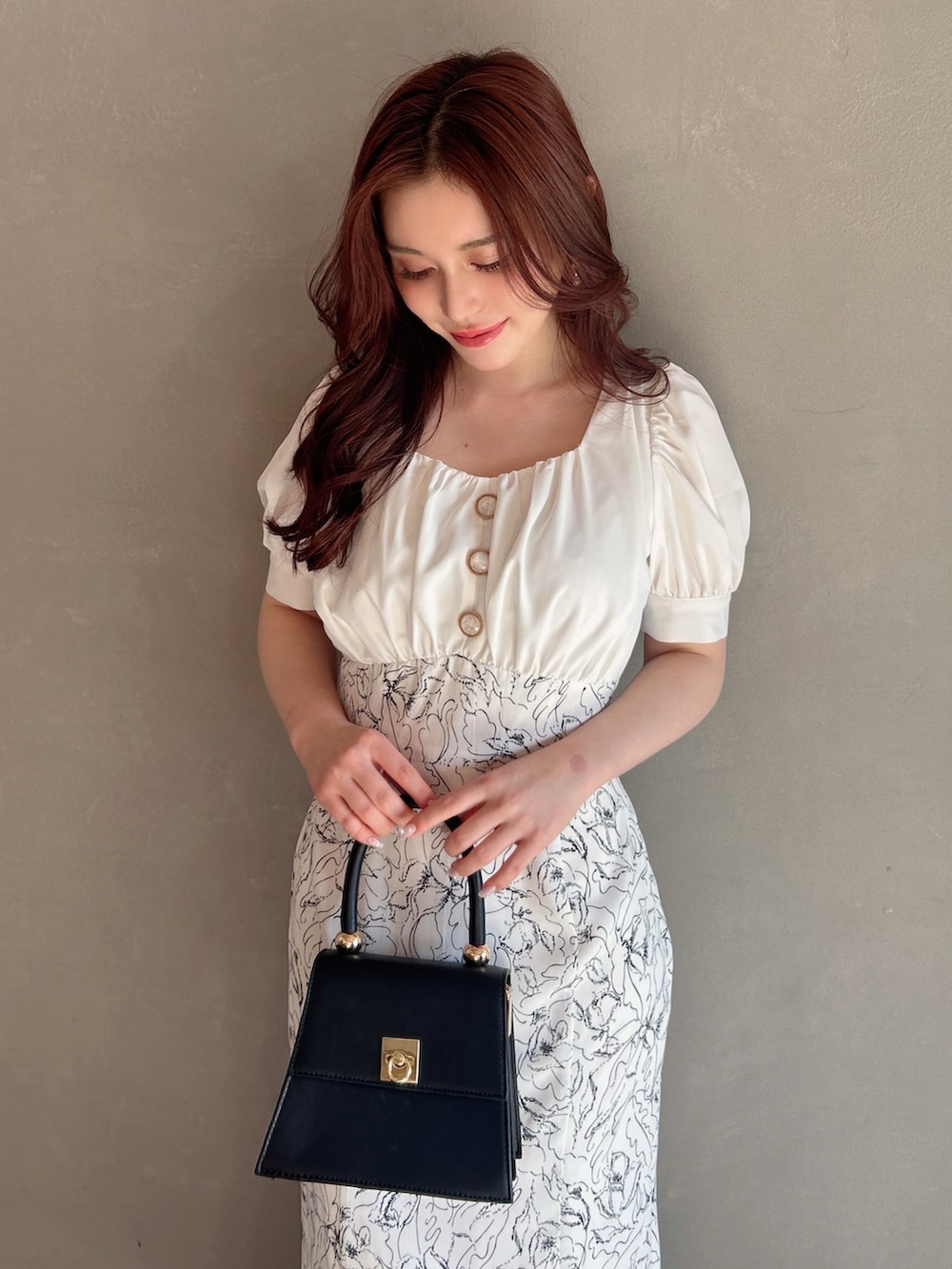 ホワイト系のワンピース、ホワイト系のパンプス、ブラック系のハンドバッグを着用したレディースの夏コーディネートの3枚目の写真