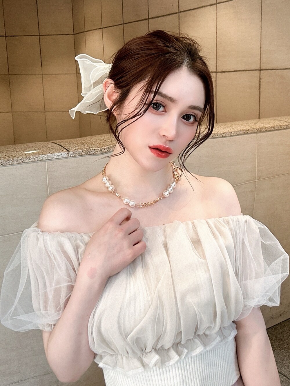 ピンク系のスカート、ホワイト系のシャツ/ブラウス、ホワイト系のハンドバッグを着用したレディースの春コーディネートの3枚目の写真