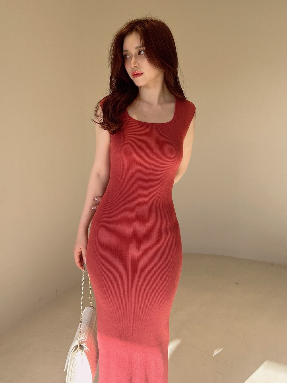 レッド系のワンピース、ホワイト系のハンドバッグを着用したレディースの夏コーディネートの2枚目の写真