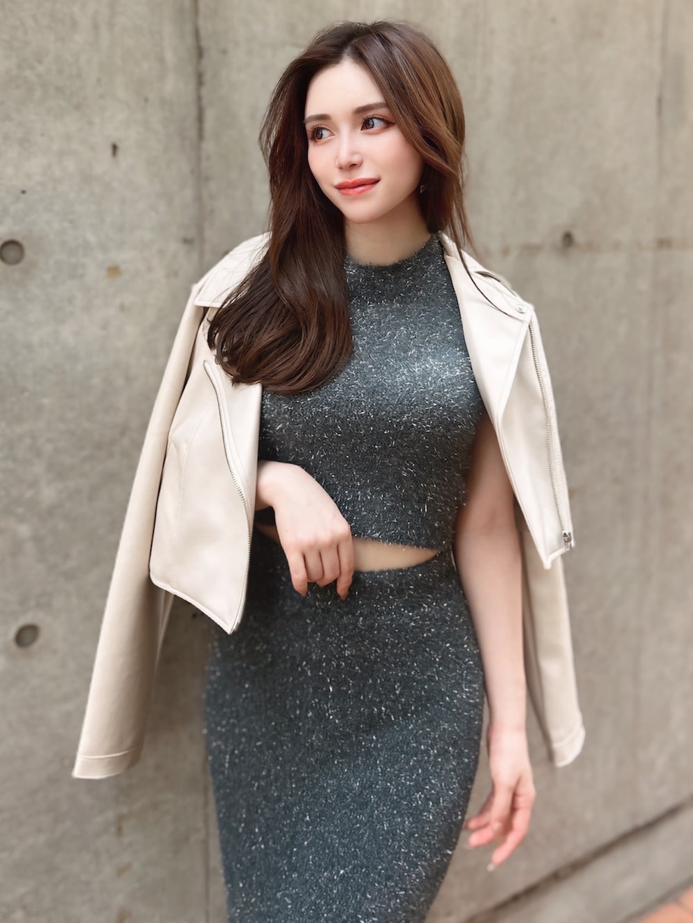 グレー系のスカート、グレー系のニット/セーター、ホワイト系のライダースジャケットを着用したレディースの夏コーディネートの2枚目の写真