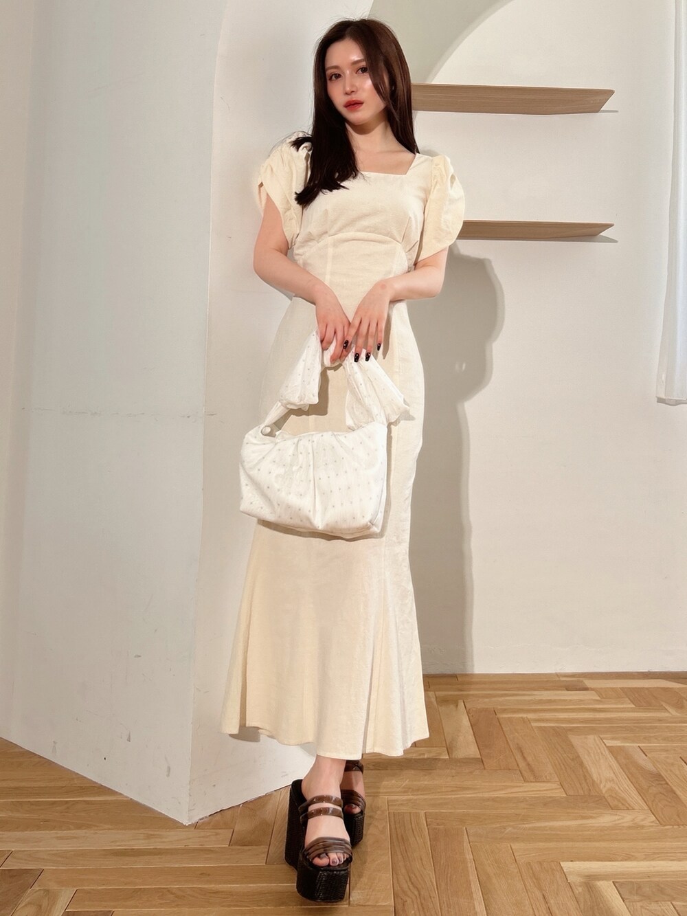 ホワイト系のワンピース、ブラック系のサンダル、ホワイト系のハンドバッグを着用したレディースの夏コーディネートの2枚目の写真