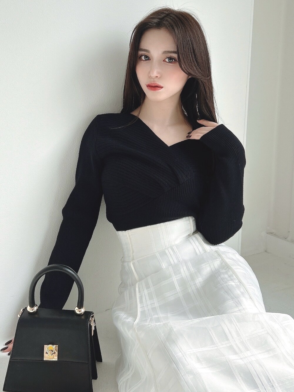 ホワイト系のスカート、ホワイト系のライダースジャケット、ブラック系のニット/セーターを着用したレディースの冬コーディネートの3枚目の写真