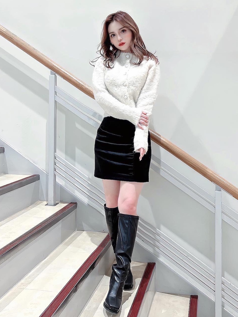 ホワイト系のニット/セーター、ブラック系のスカート、ブラック系のブーツを着用したレディースの冬コーディネートの2枚目の写真