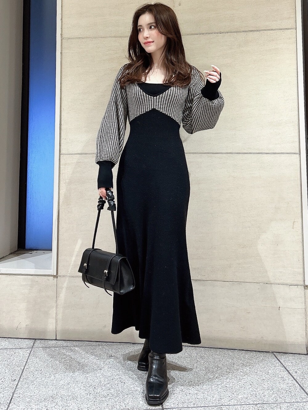 ブラック系のワンピース、ブラック系のハンドバッグ、ブラック系のブーツを着用したレディースの冬コーディネートの2枚目の写真