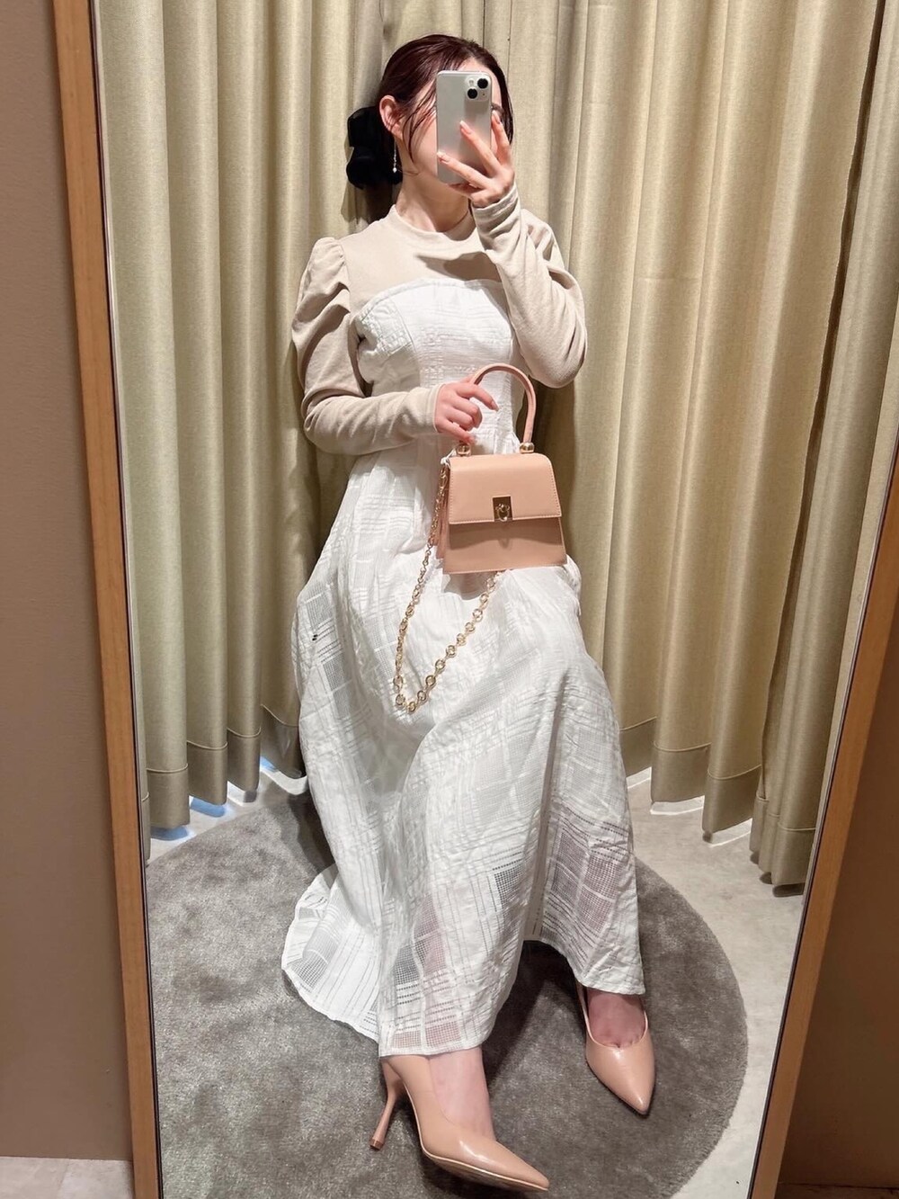 ブラック系のワンピース、ピンク系のハンドバッグ、ゴールド系のピアス（両耳用）を着用したレディースの冬コーディネートの3枚目の写真