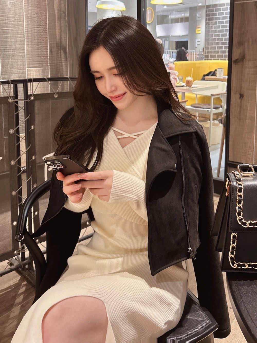 ブラック系のハンドバッグ、ホワイト系のワンピース、ブラック系のライダースジャケットを着用したレディースの冬コーディネートの4枚目の写真