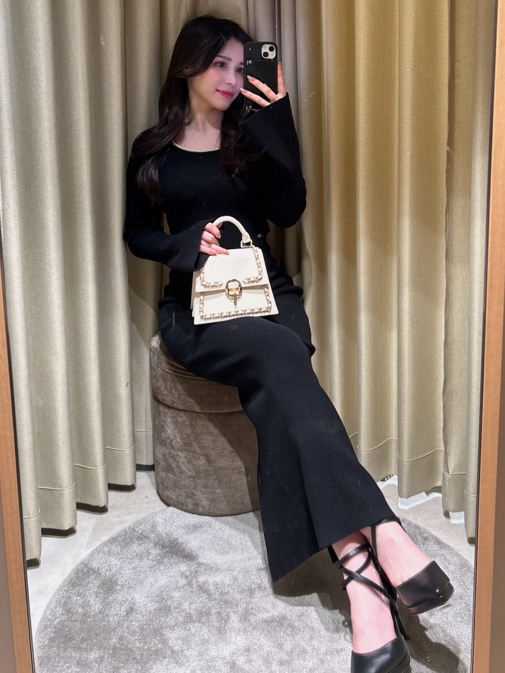 ブラック系のワンピース、ホワイト系のハンドバッグ、ブラック系のパンプスを着用したレディースの冬コーディネートの2枚目の写真