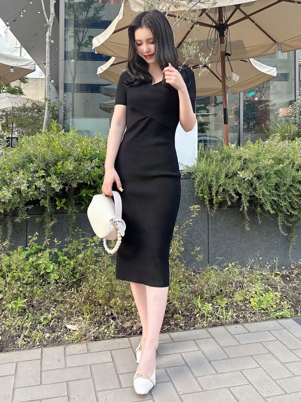 ブラック系のワンピース、ホワイト系のサンダル、ベージュ系のハンドバッグを着用したレディースの夏コーディネートの2枚目の写真