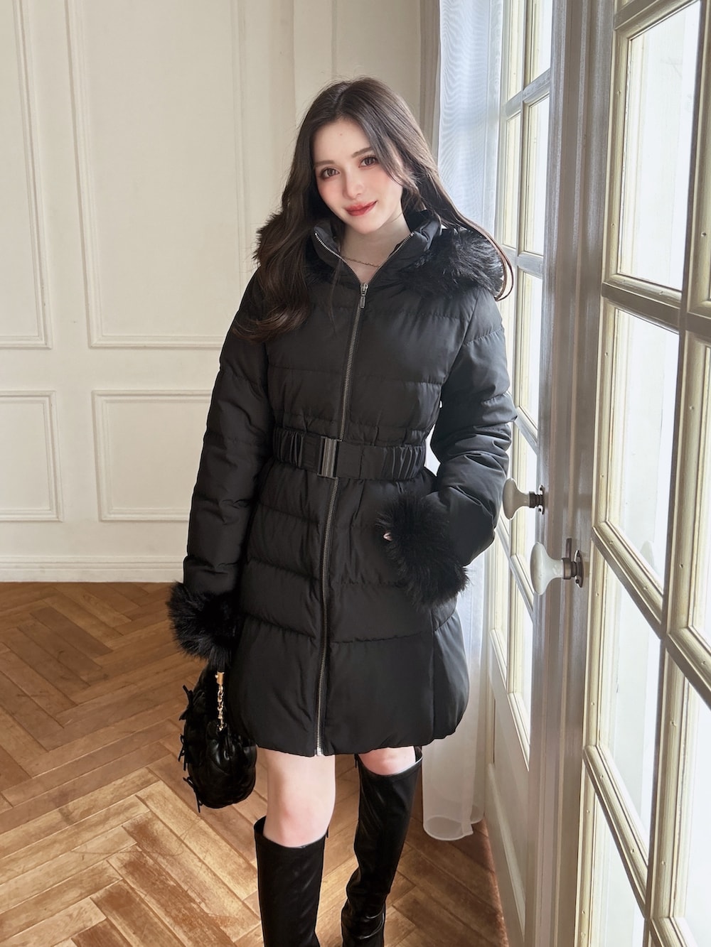 ブラック系のダウンジャケット/コート、ブラック系のブーツ、ブラック系のハンドバッグを着用したレディースの秋コーディネートの2枚目の写真