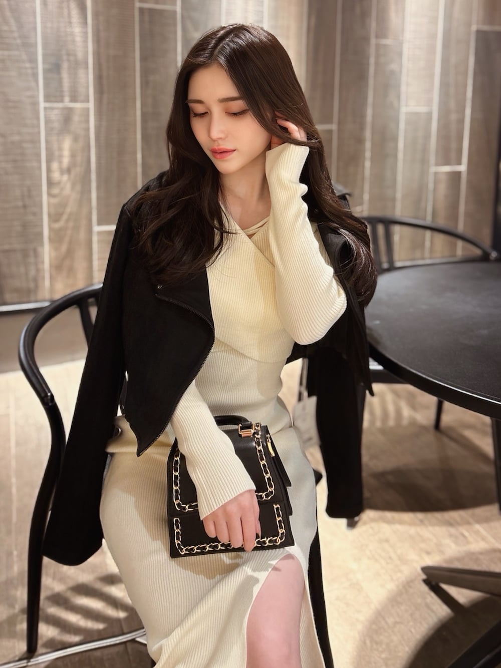 ブラック系のハンドバッグ、ホワイト系のワンピース、ブラック系のライダースジャケットを着用したレディースの冬コーディネートの3枚目の写真