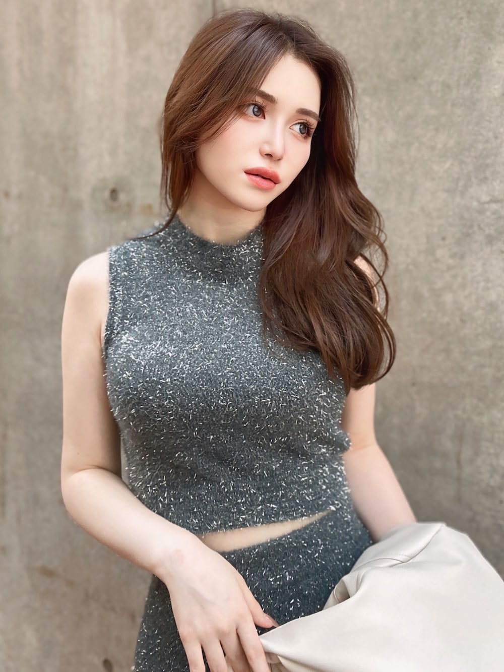 グレー系のスカート、グレー系のニット/セーター、ホワイト系のライダースジャケットを着用したレディースの夏コーディネートの3枚目の写真