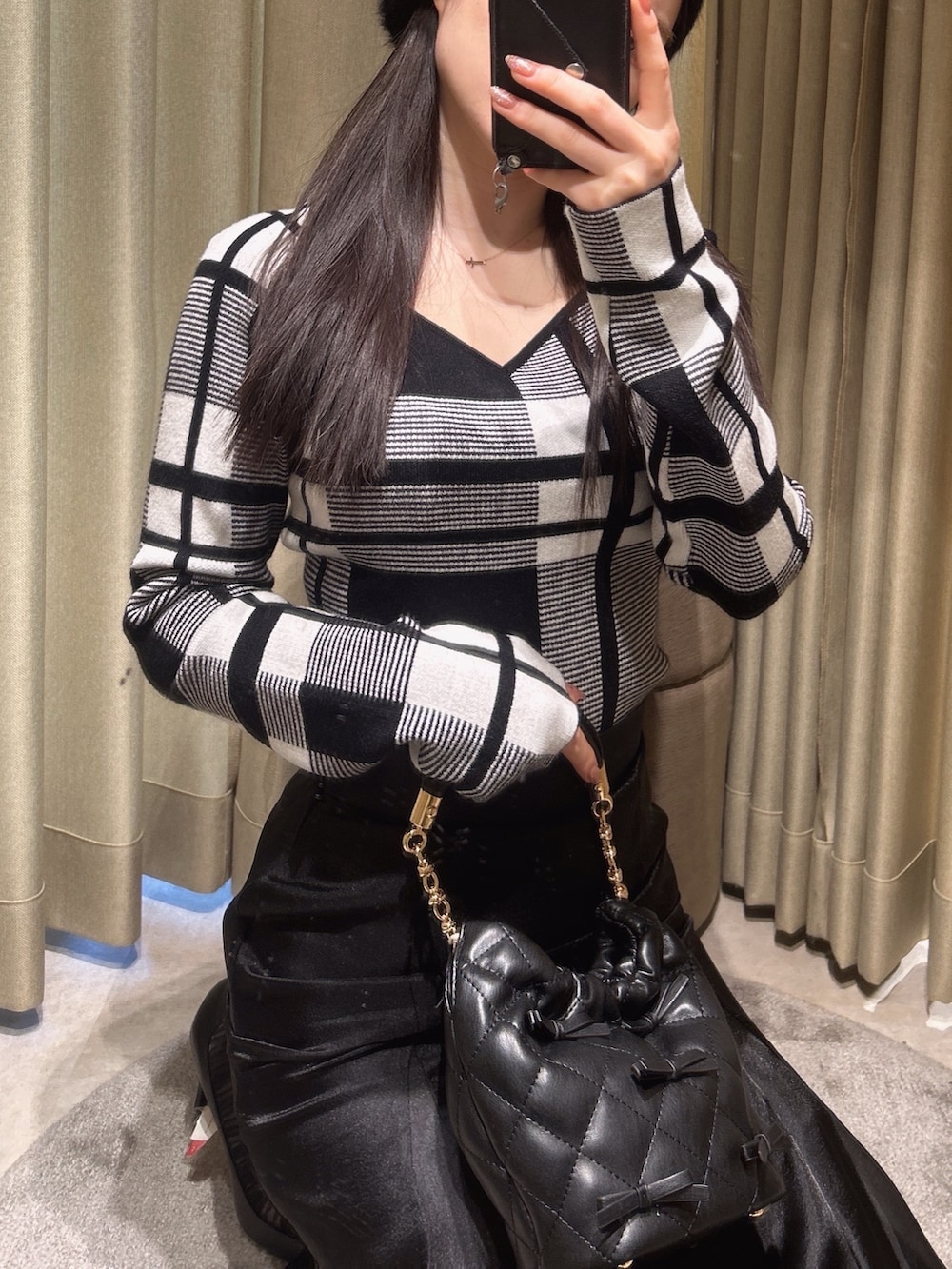 その他のニット/セーター、ブラック系のスカート、ブラック系のハンドバッグを着用したレディースの冬コーディネートの2枚目の写真