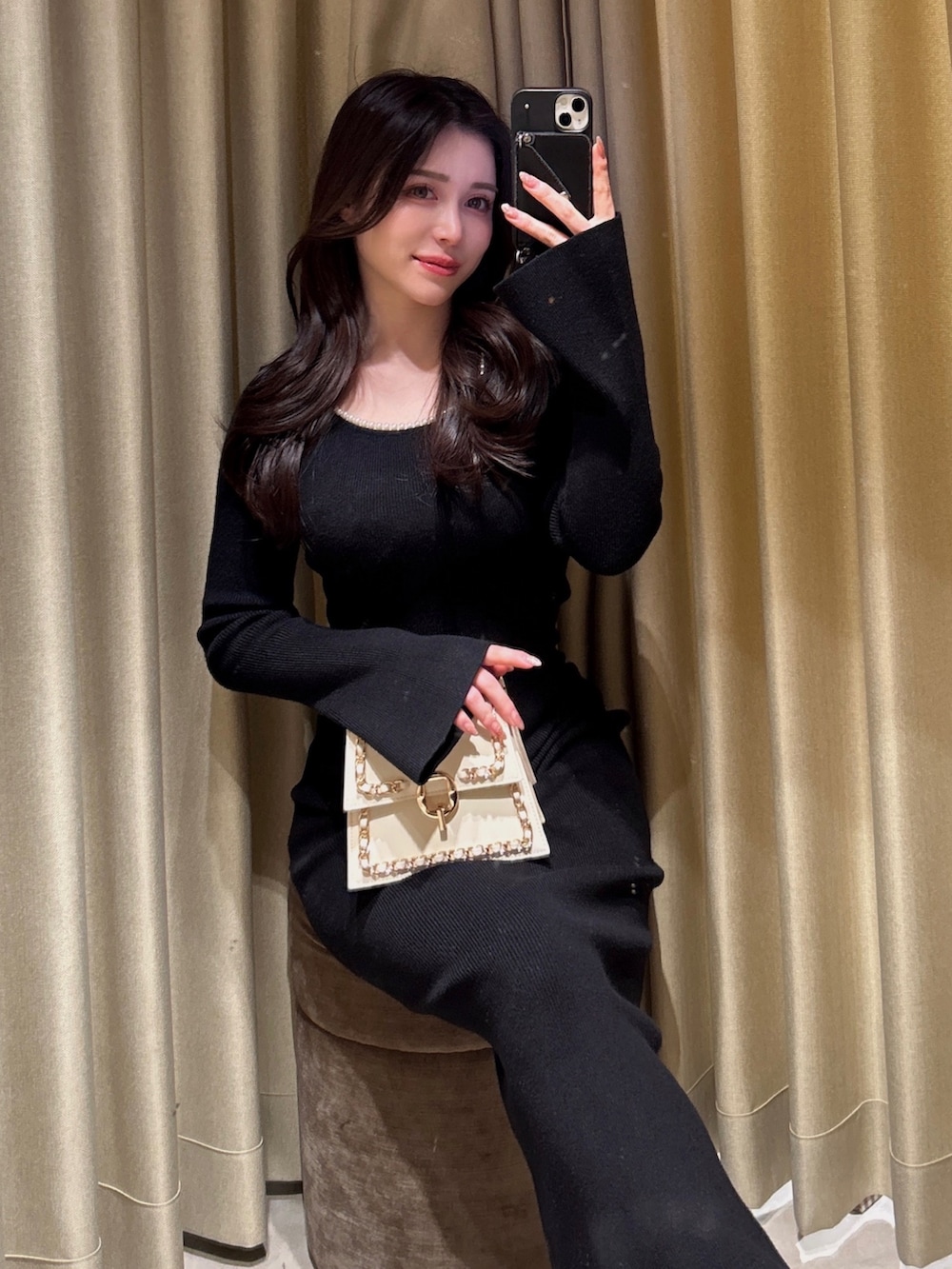 ブラック系のワンピース、ホワイト系のハンドバッグ、ブラック系のパンプスを着用したレディースの冬コーディネートの3枚目の写真