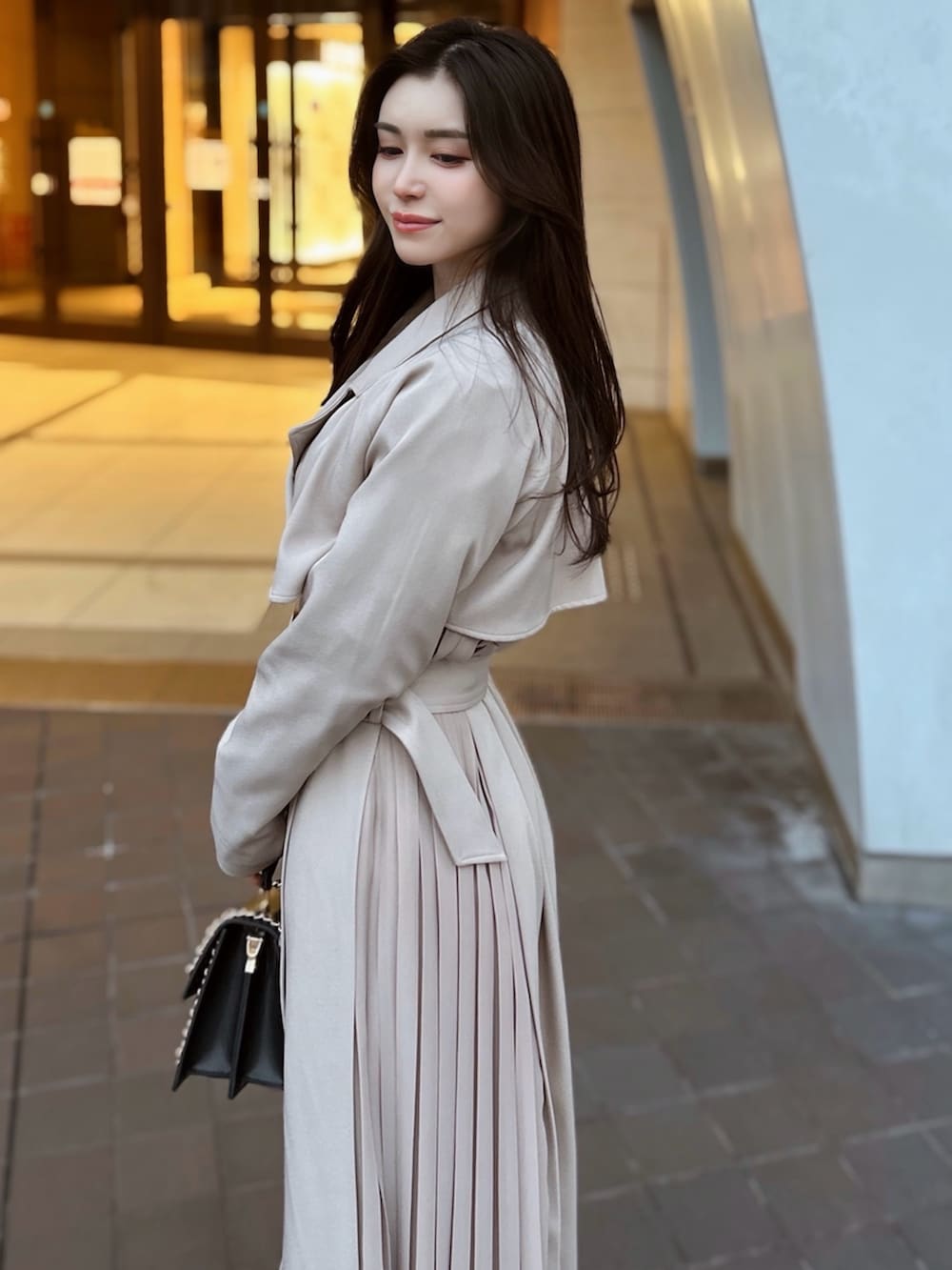 ベージュ系のトレンチコート、ブラック系のハンドバッグを着用したレディースの冬コーディネートの2枚目の写真