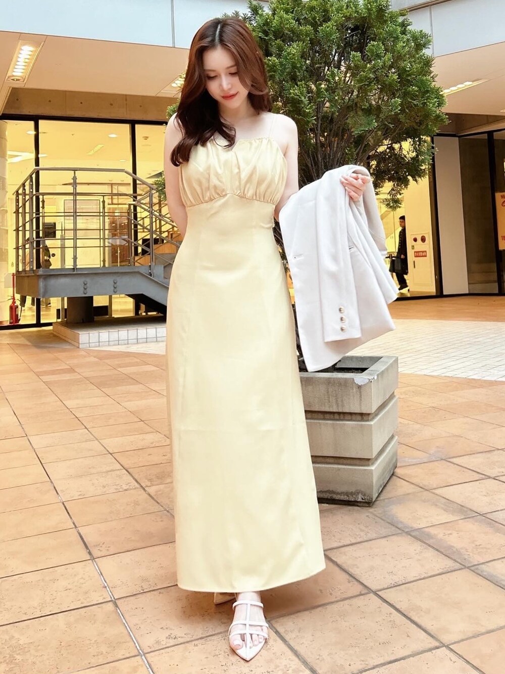 イエロー系のワンピース、ホワイト系のTシャツ/カットソー、ホワイト系のサンダルを着用したレディースの春コーディネートの2枚目の写真